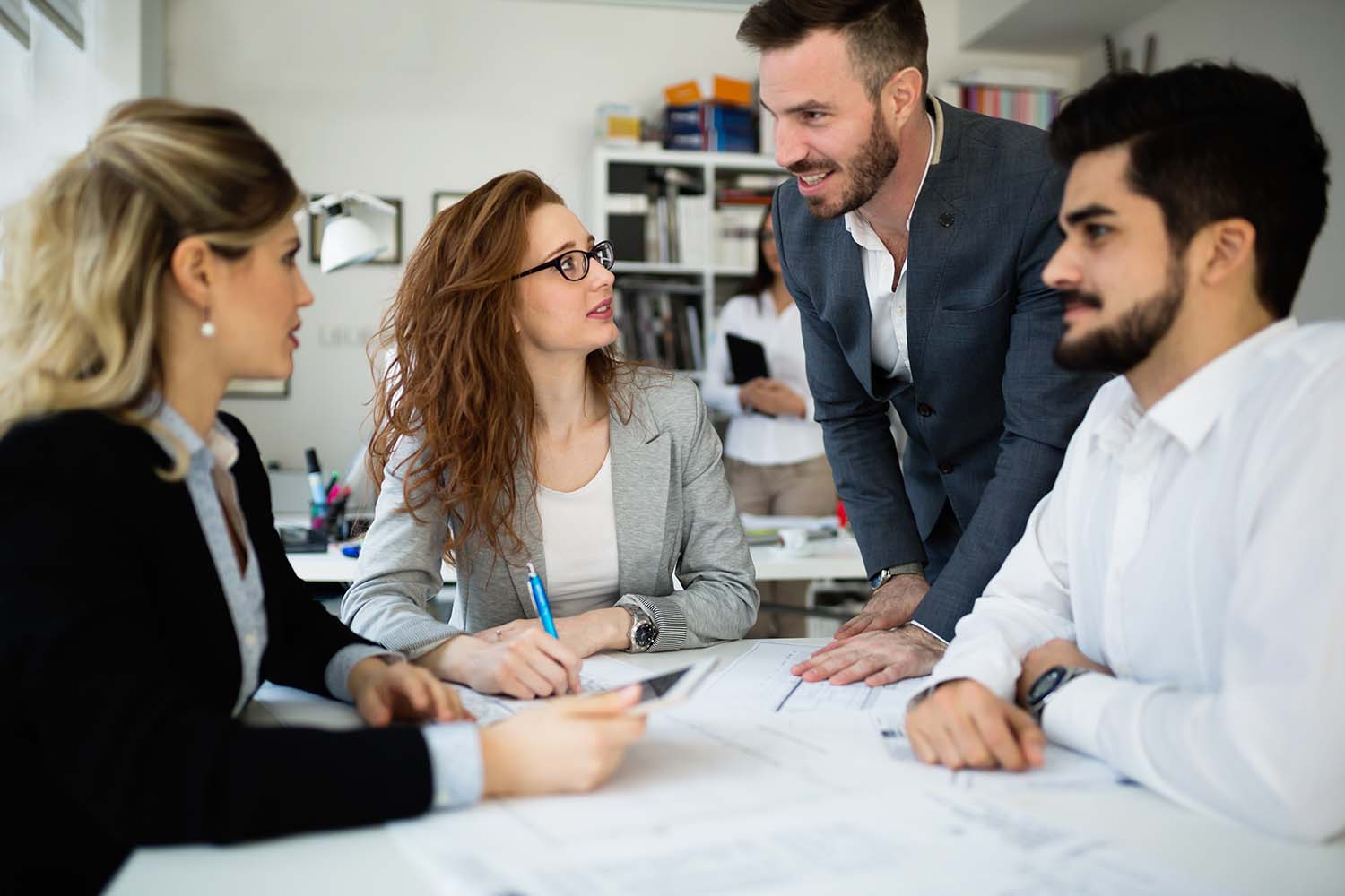 Four colleagues working through documents together at a meeting table.